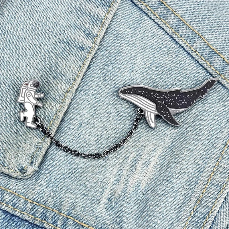 Pin's à chaîne avec astronaute en combinaison blanche et baleine noire à motifs blancs sur veste en jean bleu clair