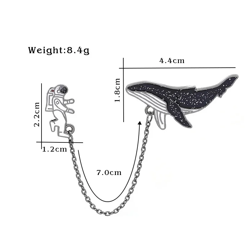 Pin's à chaîne avec astronaute en métal argenté de 2,2 cm et baleine noire à motifs blancs de 4,4 cm reliés par une chaîne de 7 cm