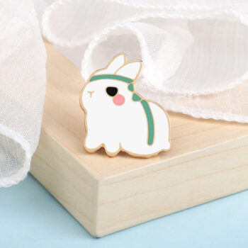 Pin's lapin mignon en métal émaillé blanc avec détails verts et rose, forme stylisée et finition soignée