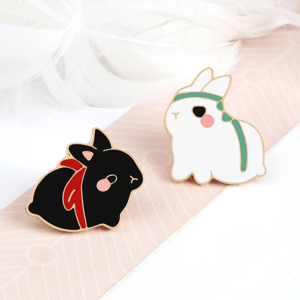 Pin's Lapin Mignon en métal émaillé, un lapin noir avec écharpe rouge et un lapin blanc avec bandeau vert, détails soignés et finition élégante