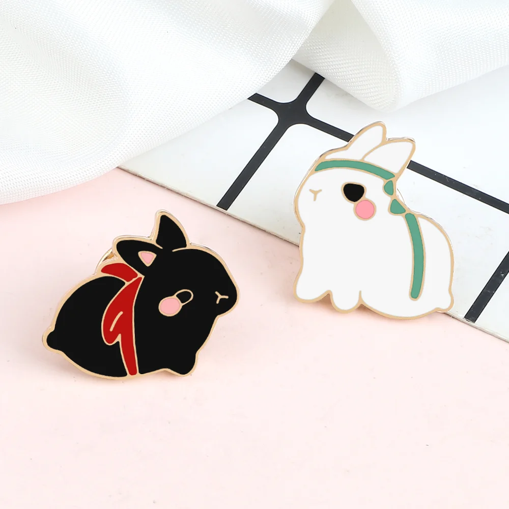 Pin's Lapin Mignon lot de deux, un lapin noir avec écharpe rouge et un lapin blanc avec bande verte, finition émaillée brillante
