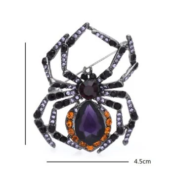 Broche araignée à perle avec cristaux violets et orange, détail des pattes articulées et perle centrale en forme de goutte
