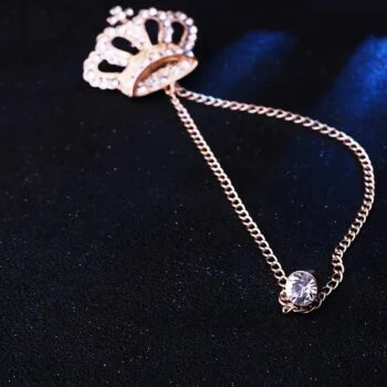 Broche à chaine couronne homme en métal doré avec détail chaîne fine et fermoir rond orné d'un strass
