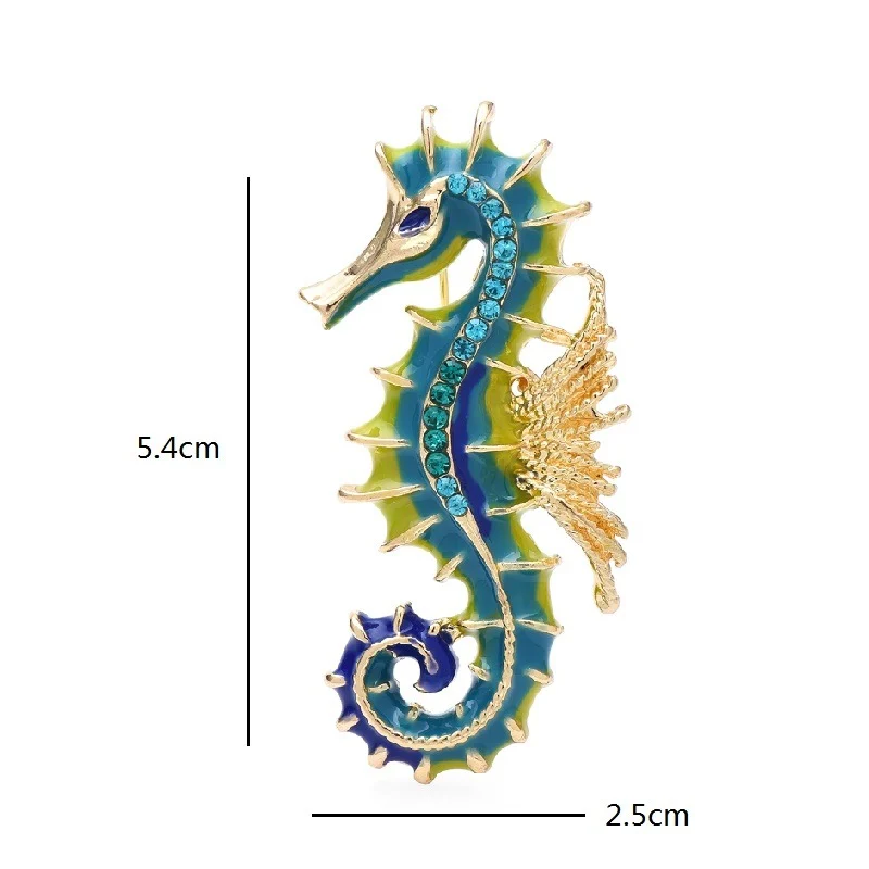 Broche hippocampe en métal doré avec émail bleu et vert, détail des strass bleus sur le corps, dimensions 5,4 cm x 2,5 cm