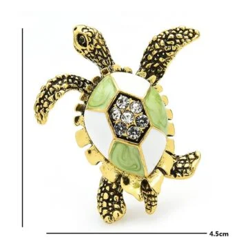 Broche tortue vintage en métal doré avec émail blanc et vert, ornée de strass sur la carapace, détail soigné des pattes texturées