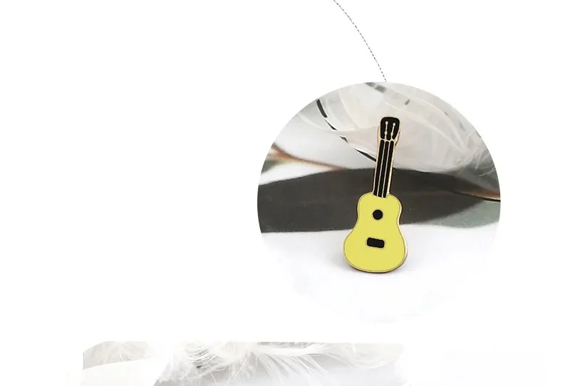 Pin's musique en forme de guitare jaune avec cordes noires, détail du design travaillé et finition soignée