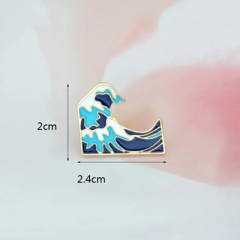 Pin's Vague en métal doré avec émail bleu clair, bleu foncé et blanc représentant une vague stylisée, dimensions 2 cm sur 2,4 cm